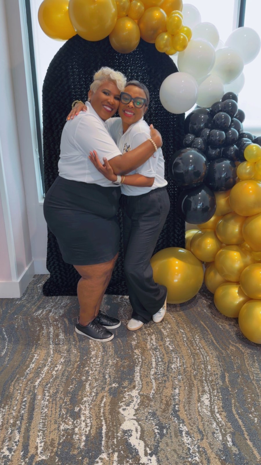Two community members in white polos sharing a hug at the gathering