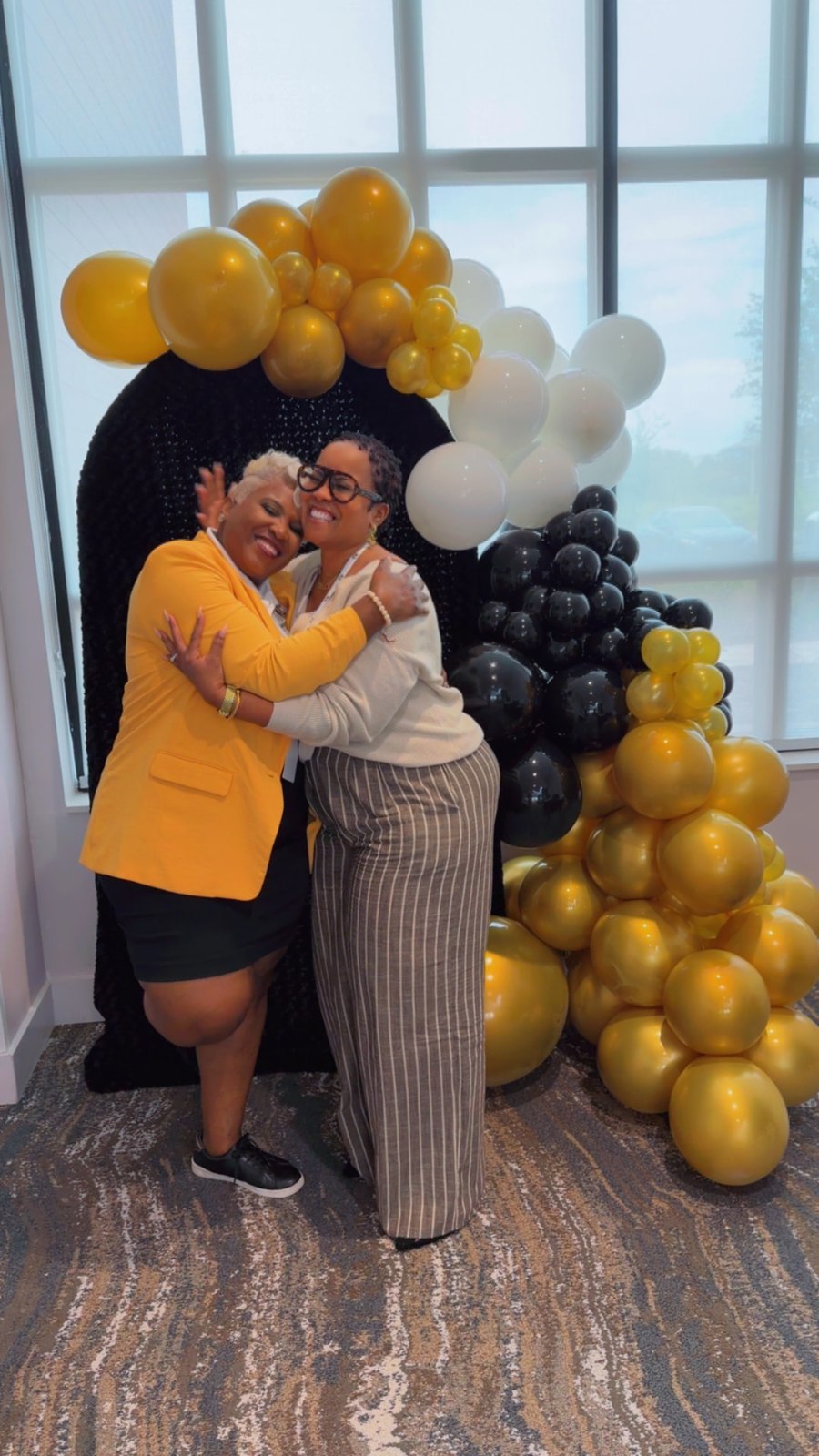 Toya embracing a member beside the black, white and gold balloons