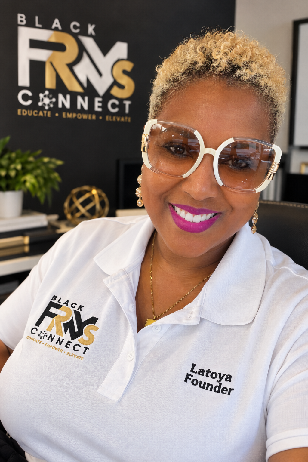 Founder Latoya Wise smiling in a white Black FRMs Connect polo embroidered with Latoya, Founder, in front of the Black FRMs Connect logo