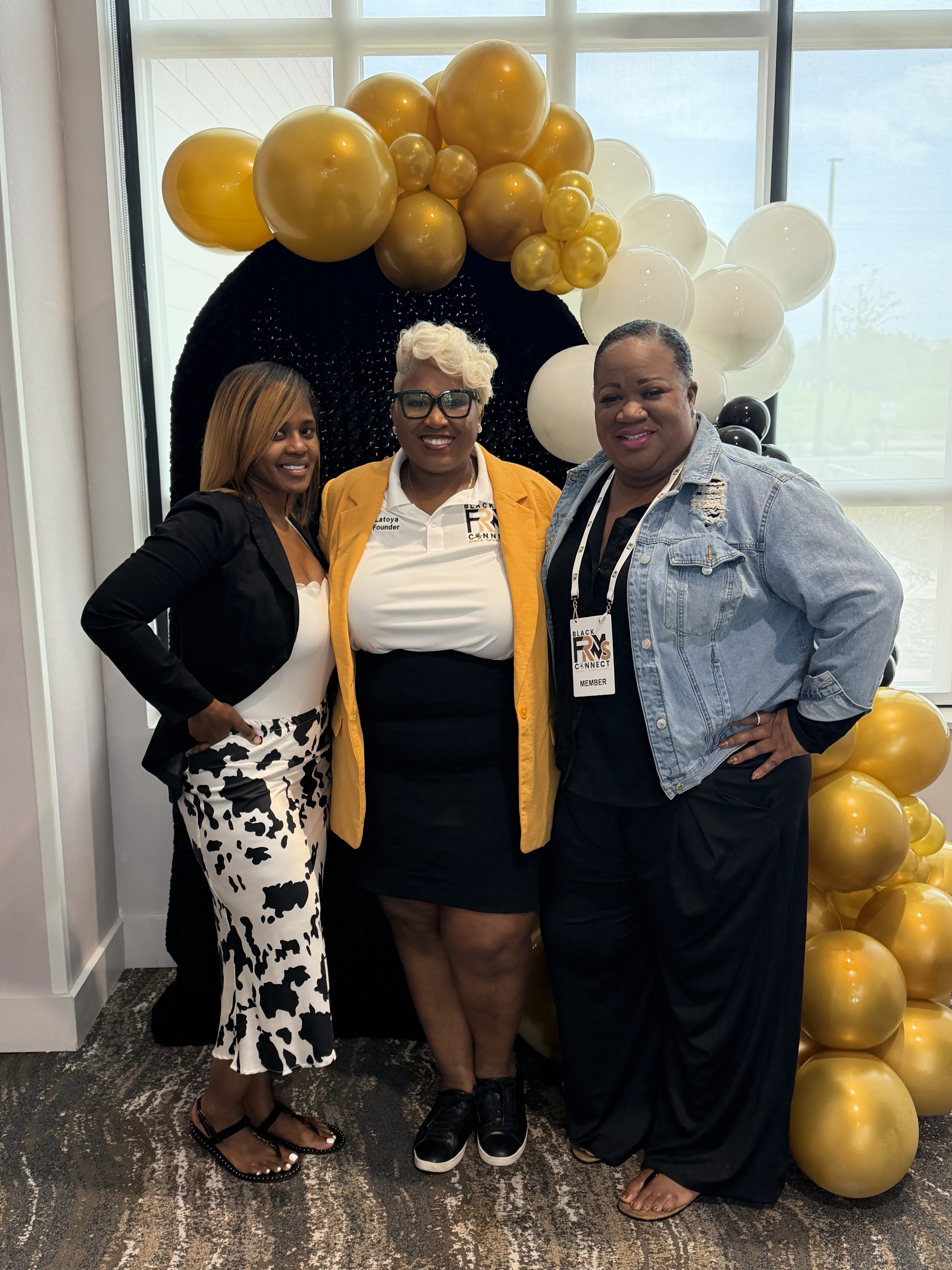 Toya and two members posing together at the balloon arch